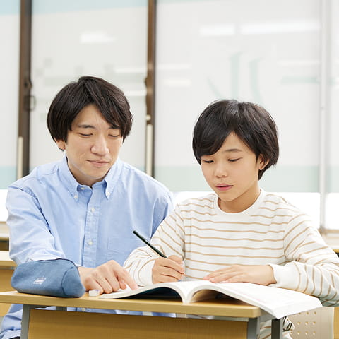 講師が児童のノートを見ながら問題を解説している様子